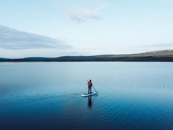 Paddleboarder on a glassy lake surrounded by forest on Texada Island during a full-day rental